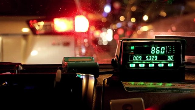 Waiting in night city traffic inside taxi car. The digital taxi meter on the dashboard of cab shows kilometer and cost.