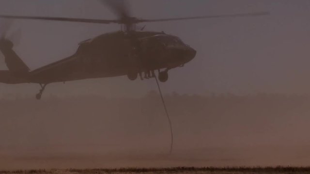 Soldiers fast-rope from an helicopter flying over