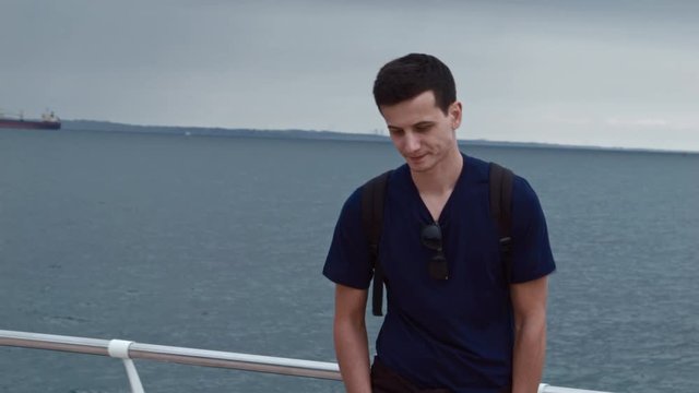 4K A handsom man is standing on a pier and after a while walking away with saying something.