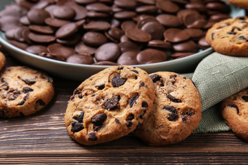 Tasty cookies with chocolate chips on wooden table