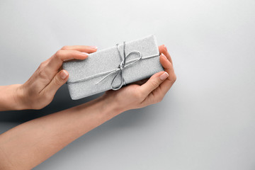 Female hands with manicure holding gift box on light background