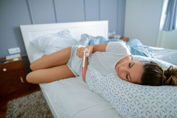 Baby is coming ! Young beautiful girl lying in her bed with pregnancy test in her hands. Looking confused and worried.