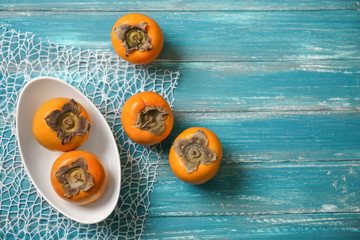 Tasty ripe persimmons on color wooden table