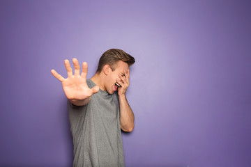 Stressed young man showing Stop gesture on color background