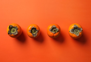 Tasty ripe persimmons on color background, top view