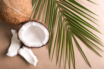 Fototapeta na wymiar Ripe coconuts and palm leaf on color background