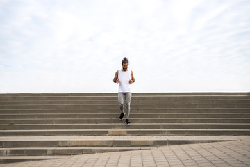 young man with long hair wearing sport wear going up and down  the stairs