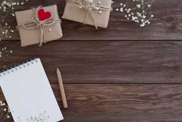 Two gifts in craft paper, red heart decoration and branches of little flowers on the wooden background. Romance, Spring, St. Valentine's and Mother's Day concept. Top view, copy space, mock up