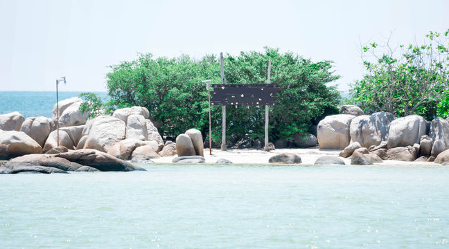 Small island with big rocks and wooden handmade blank sinage in a beach resort