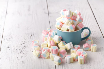 Colorful marshmallows in a cup, over wood background