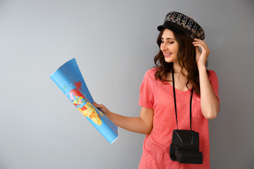 Female tourist with map on grey background