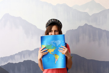 Female tourist with map near grey wall