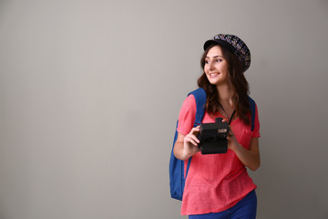Female tourist with camera on grey background