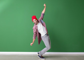 Handsome young man dancing near color wall