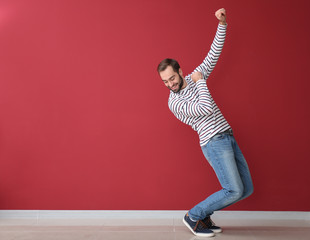 Handsome young man dancing near color wall