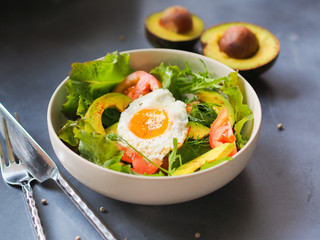 Avocado salad bowl with fried egg on top  for diet food or healthy eating concept.