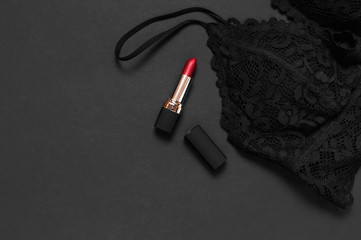 Black lace bra underwear, red lipstick on dark background top view flat lay with copy space. Female...