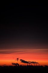 Problem of ecology. The smoke from the chimneys against the evening sky. Sunset and the contour of the city