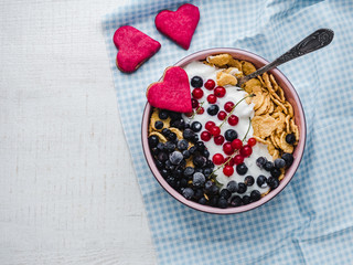 Healthy breakfast. Cereal biscuits in pink glaze, cornflakes, yogurt and fresh berries on the background of white boards. Close-up, top view, isolated. Concept of healthy and delicious food