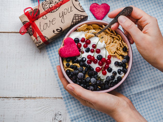 Festive and Healthy breakfast for loved ones. Cereal biscuits in pink glaze, cornflakes, yogurt, fresh berries on the background of white boards. Close-up, top view. Concept of healthy, delicious food