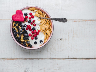 Healthy breakfast. Cereal biscuits in pink glaze, cornflakes, yogurt and fresh berries on the background of white boards. Close-up, top view, isolated. Concept of healthy and delicious food