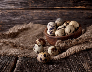 Quail eggs in a wooden  plate on the old background. Rustic style on dark wood background.