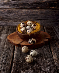 Quail eggs in a wooden  plate on the old background. Rustic style on dark wood background. Top view.