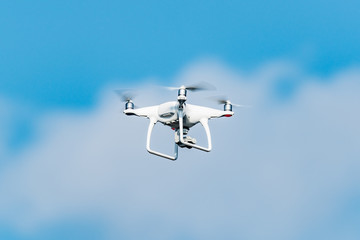 White quadrocopter above in the blue sky.