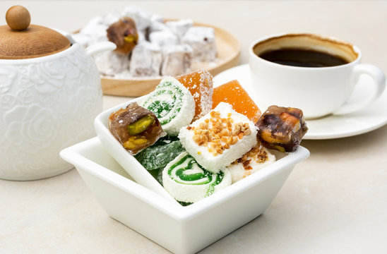 Assorted traditional turkish delight. Oriental dessert in a white glass squar plate with a cup of coffee