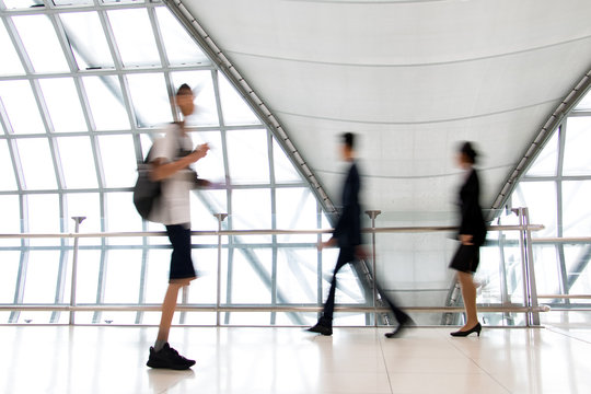A people walking in motion blur on white corridor with large windows. Blurred people walking in a modern building. Abstract image of people in the lobby.