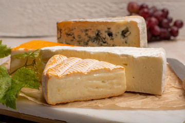 Tasting plate with four France cheeses, cream brie, marcaire, saint paulin and blue auvergne cheese, served with fresh ripe grapes