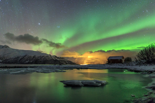 The Northern Lights illuminates the wooden cabin Svensby Lyngen Alps Troms√∏ Lapland Norway Europe