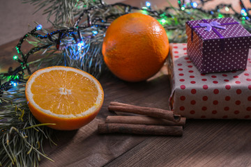 Boxes with gifts, oranges, cinnamon and Christmas tree - not a wooden background. New Year gifts. Winter mood. The aroma of holidays.