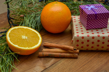 Boxes with gifts, oranges, cinnamon and Christmas tree - not a wooden background. New Year gifts. Winter mood. The aroma of holidays.