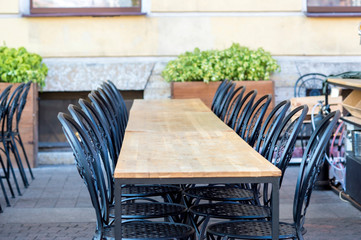 Deserted interior of a summer cafe in the off-season. Empty table and rows of chairs are on the sidewalk.