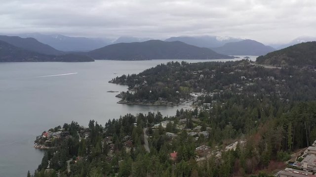 Aerial view over Burrard Inlet, ocean and island with boat and mountains in beautiful British Columbia. Canada.