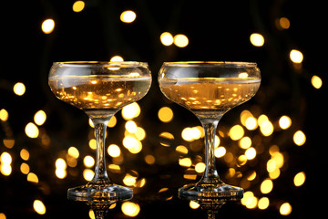 Glasses of tasty champagne on dark background against defocused lights