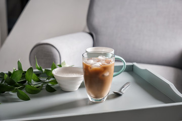 Glass of tasty frappe coffee and bowl with sugar on table