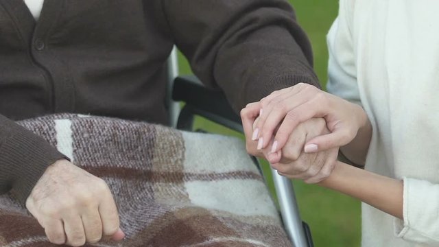 Woman holding hand of patient in wheelchair, volunteer program, charity concept