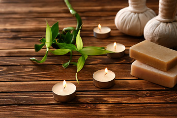 Beautiful spa composition with burning candles and soap bars on wooden table