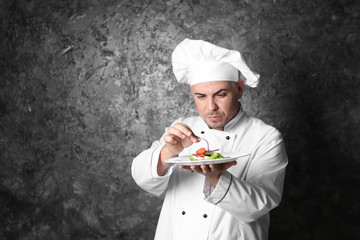 Male chef with tasty salad on grey background