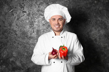 Male chef with vegetables on grey background
