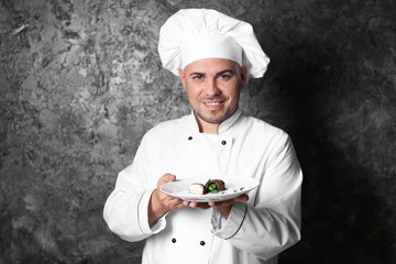 Male chef with tasty dessert on grey background