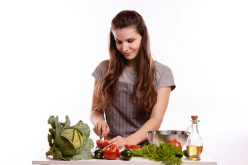 happy adult woman with various fresh vegetables on kitchen table looking at camera