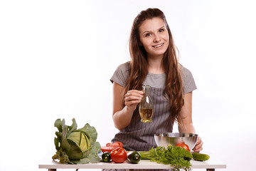 happy adult woman with various fresh vegetables on kitchen table looking at camera