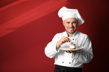 Male chef with tasty dessert on color background