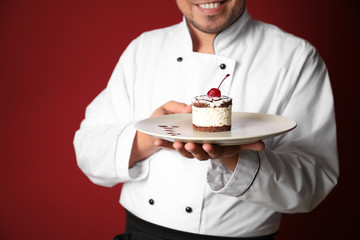 Male chef with tasty dessert on color background, closeup