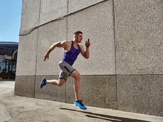 sport man starting running. Young man jogging front cement wall