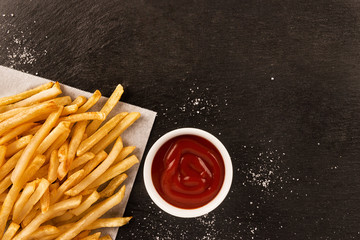 French fries with ketchup on dark background, directly above. Close up. - 239359129