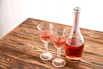 Glasses and bottle of pink champagne on wooden table
